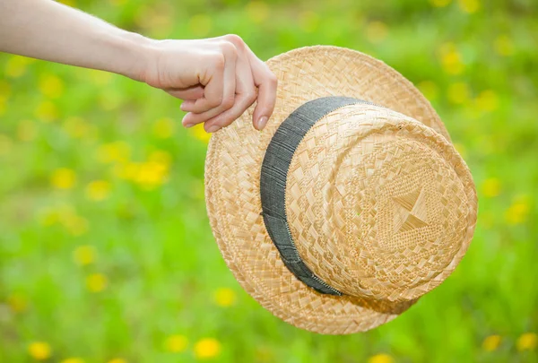 Female hand holding a straw hat — Stock Photo, Image