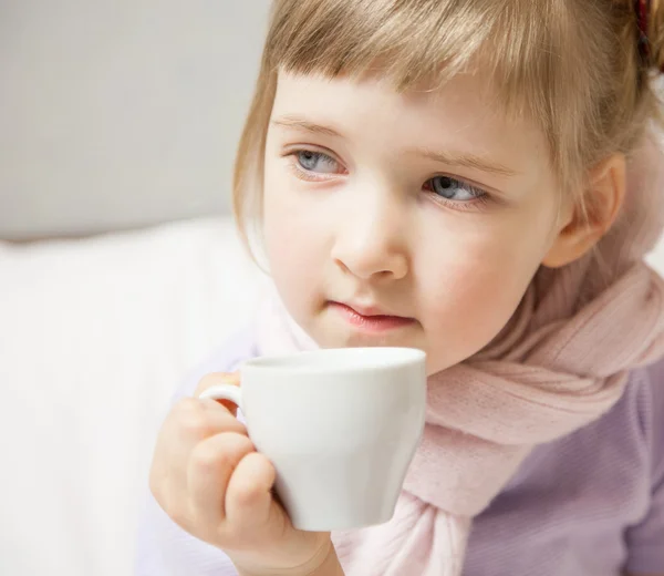 Маленькая девочка сидит в кровати с чашкой — стоковое фото