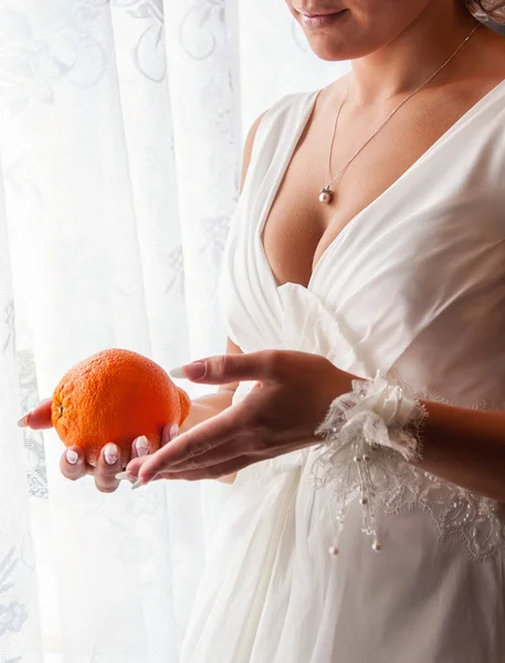Schöne unkenntliche Braut mit einer Orange — Stockfoto