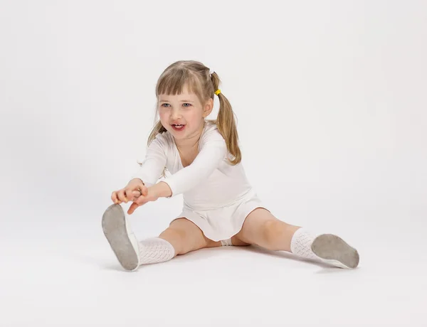 Kleines Mädchen sitzt und macht Sport — Stockfoto