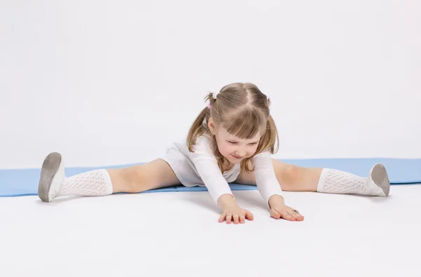 Kleines Mädchen sitzt und macht Sport — Stockfoto