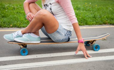 Tanınmayan bir longboard üzerinde oturan kız 
