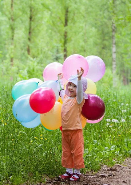 Petite fille tenant beaucoup de ballons de couleur — Photo