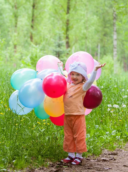 Little girl gazdaság sok színes léggömbök — Stock Fotó