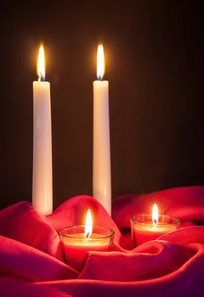 Beautiful candles on red cloth — Stock Photo, Image