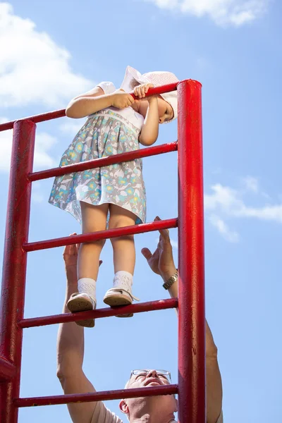 Grandfather supporting a  girl climbing a stairs — Stock Photo, Image