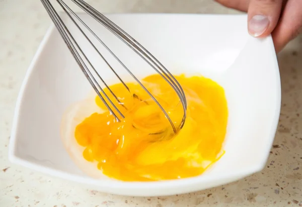 Whipping eggs with a metal whisk — Stock Photo, Image