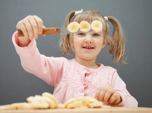 Маленькая девочка режет спелый банан — стоковое фото