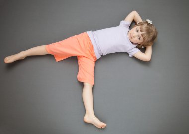 Smiling little girl lying on the floor clipart