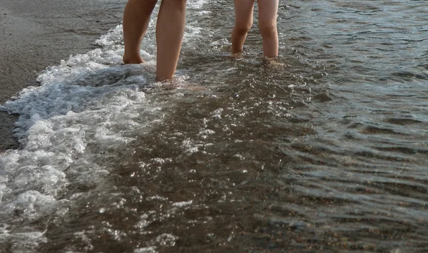 Piernas caminando cerca de la orilla del mar — Foto de Stock