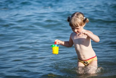 Küçük kız bir denizden su taşıyan
