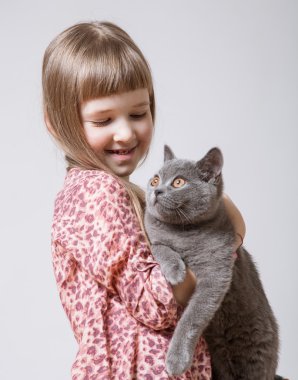Bir kedi tutan mutlu küçük kız 
