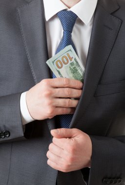 Bir cebinde dolar/koyarak dolar tutan işadamı
