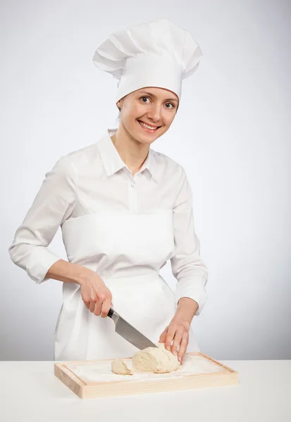 Lächelnde Köchin schneidet rohen Teig — Stockfoto