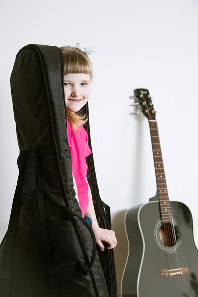 Petite fille souriante cachée dans la couverture d'une guitare — Photo