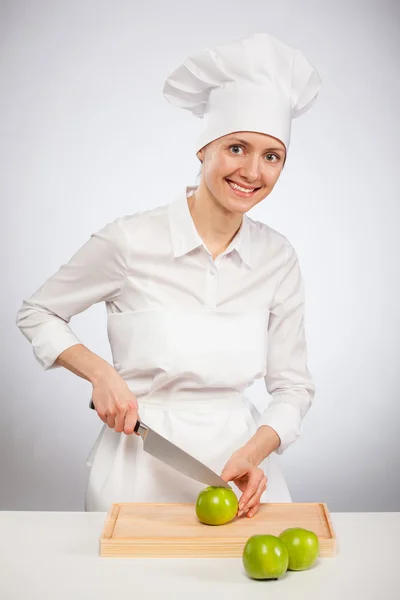 Beautiful young female cook cutting an apple — Stock Photo, Image