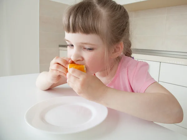 Hübsches kleines Mädchen beißt in eine Orange — Stockfoto