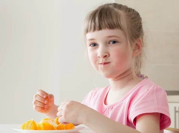 Happy little girl eating a tasty orange — Stock Photo, Image