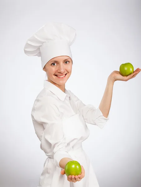 Beautiful young female cook showing an apple — Stock Photo, Image