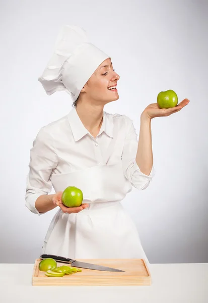 Beautiful young female cook showing an apple — Stock Photo, Image