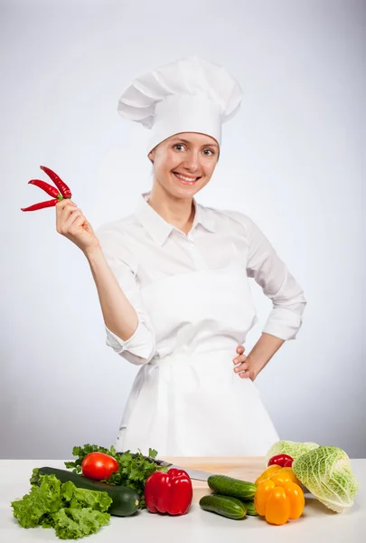Feliz joven y sonriente cocinera sosteniendo cayennes frescas — Foto de Stock