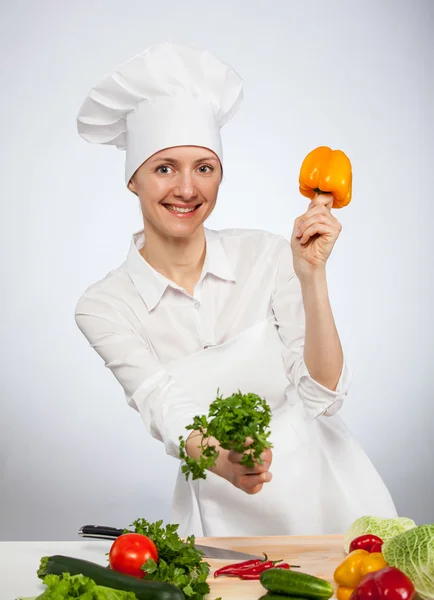 Smiling young cook holding parsley and yellow pepper — Stock Photo, Image