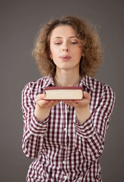 Jovem mulher soprando poeira sobre um livro — Fotografia de Stock