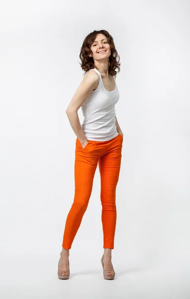 Happy smiling young woman in orange pants posing on neutral back — Stock Photo, Image
