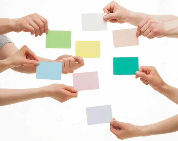 Mãos segurando cartões de papel coloridos — Fotografia de Stock