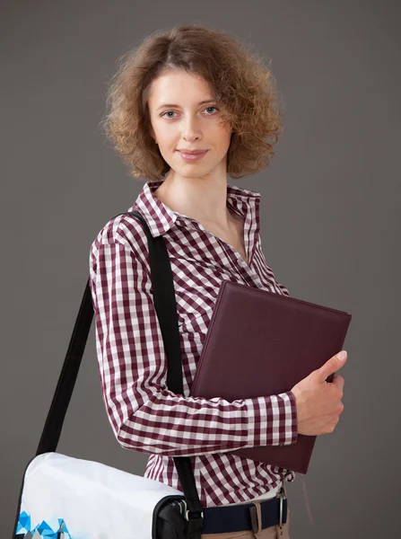 Portrait of a young woman holding a book and a briefcase — Stock Photo, Image