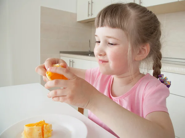 Счастливая маленькая девочка ест апельсин — стоковое фото