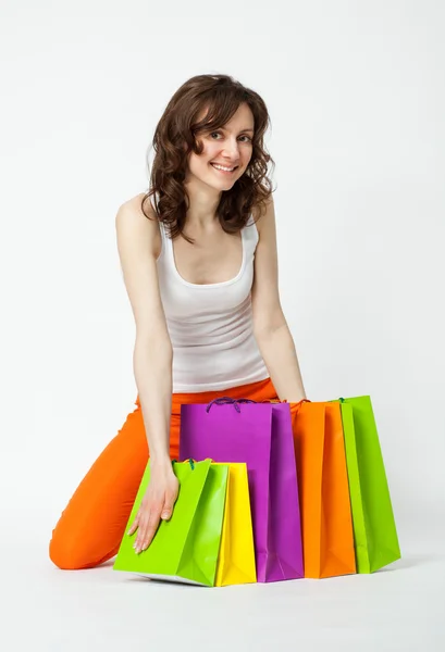 Playful young brunette in orange pants sitting on the floor with — Stockfoto