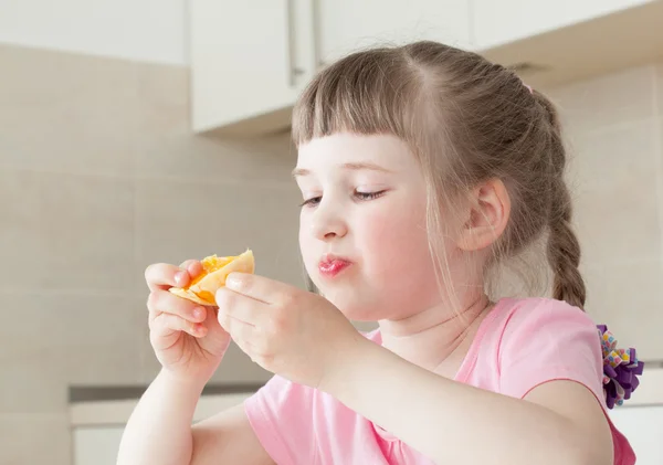 Lycklig liten flicka äter en välsmakande orange — Stockfoto