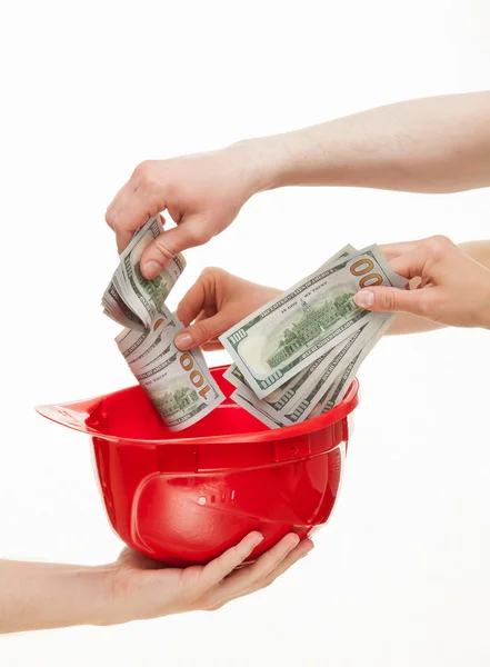 Hands putting money in hard hat — Stockfoto