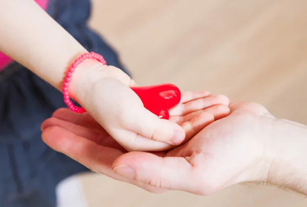 Filha e seu pai segurando um coração vermelho em suas mãos — Fotografia de Stock