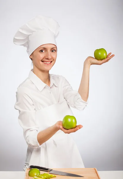 Bela jovem cozinheira mostrando uma maçã — Fotografia de Stock