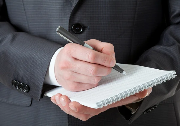 Hombre de negocios irreconocible sosteniendo un cuaderno vacío y un bolígrafo — Foto de Stock