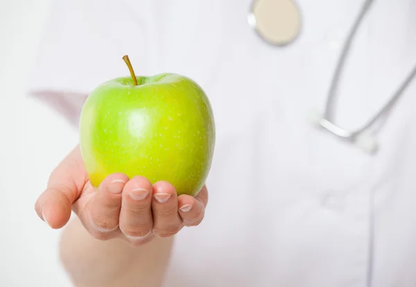 Médico segurando uma maçã verde fresca — Fotografia de Stock