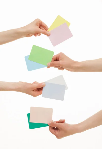 Quattro mani che tengono carte di carta colorate — Foto Stock