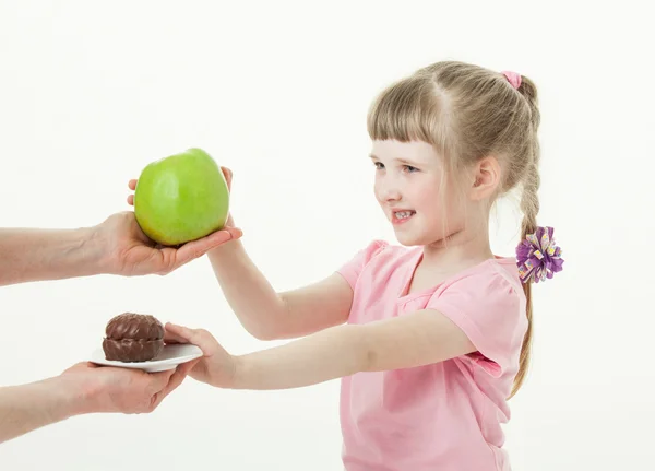 Menina escolhendo maçã e recusando um bolo — Fotografia de Stock