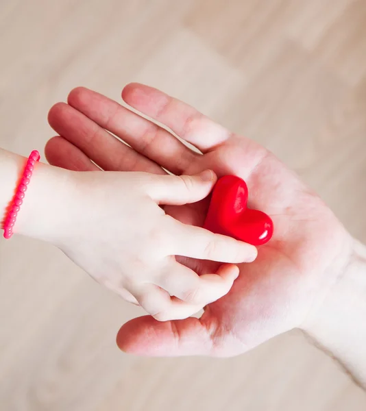 Dotter och hennes pappa håller ett rött hjärta i sina händer — Stockfoto