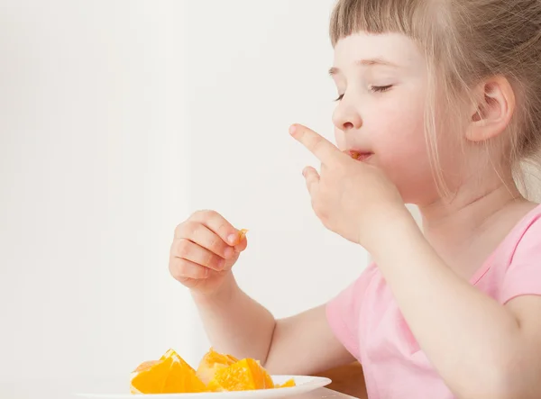 Menina comendo uma laranja — Fotografia de Stock