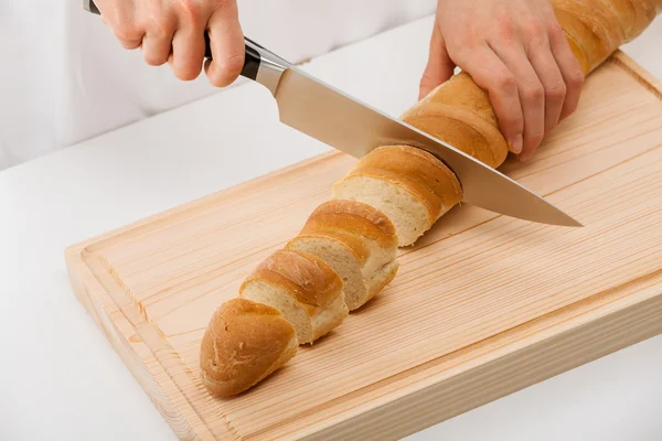 Cook cutting bread on wooden board — Stock Photo, Image