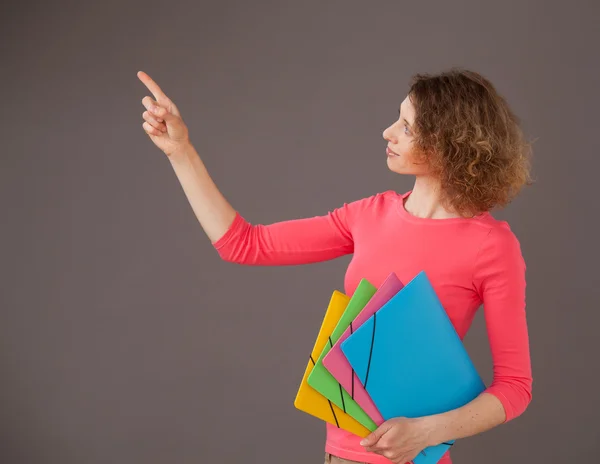 Młoda kobieta trzymając foldery i wskazując coś się — Zdjęcie stockowe