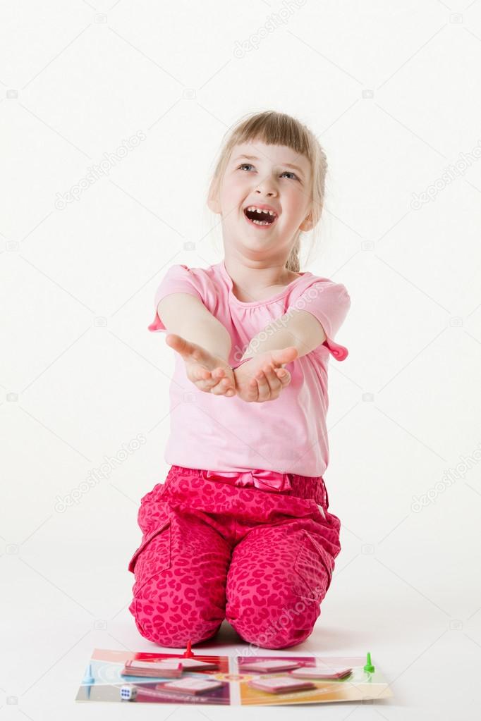 Happy little girl sitting on the floor, reaching out her palms