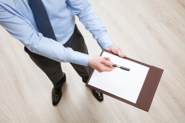 Businessman holding a clipboard and proposing a pen