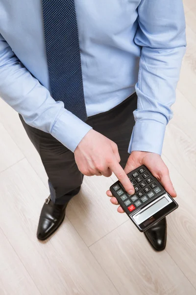 Empresario sosteniendo una calculadora y contando — Foto de Stock