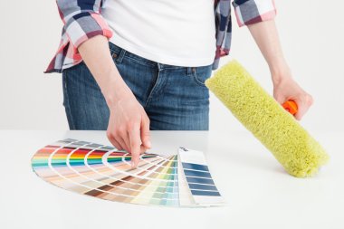 Woman examining palette and holding a roller clipart