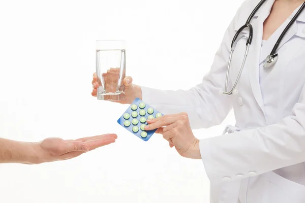 Doktor navrhuje sklenici vody a tablety — Stock fotografie