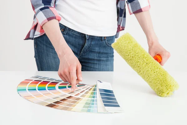 Frau untersucht Palette und hält Rolle in der Hand — Stockfoto